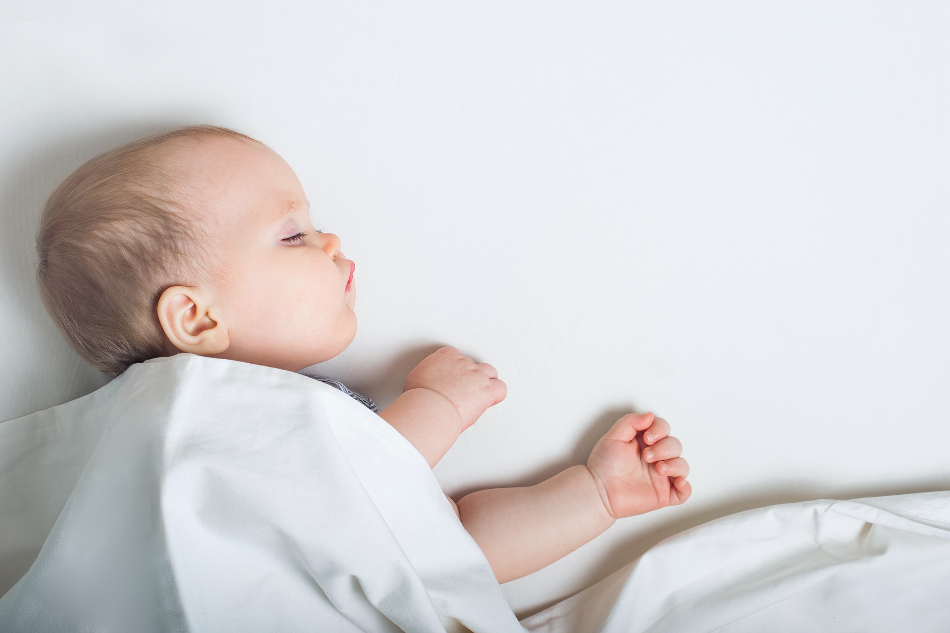 Baby sleeps on bed. Infant development concept, toddler restful sleep, teething, colic.